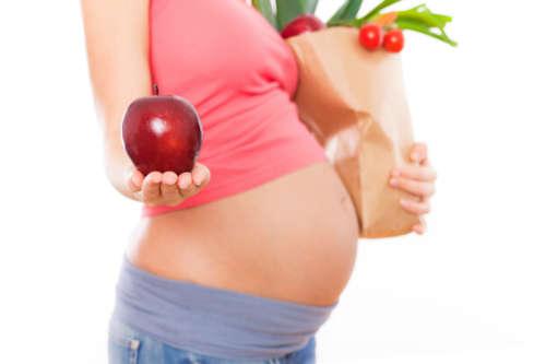 фотография живота беременной женщины с яблоком в руке